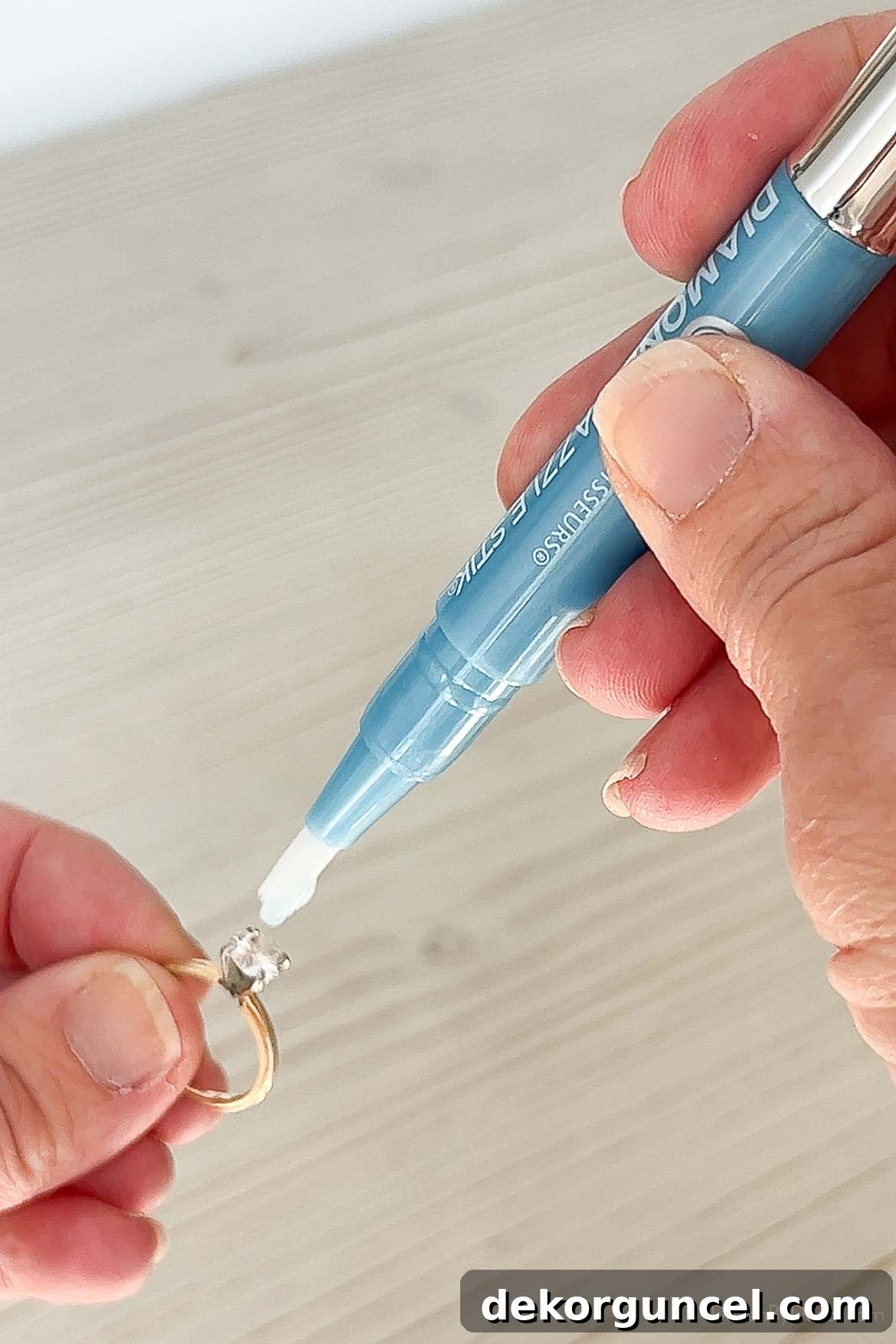 Hand holding a diamond cleaning pen, cleaning a sparkling diamond ring.