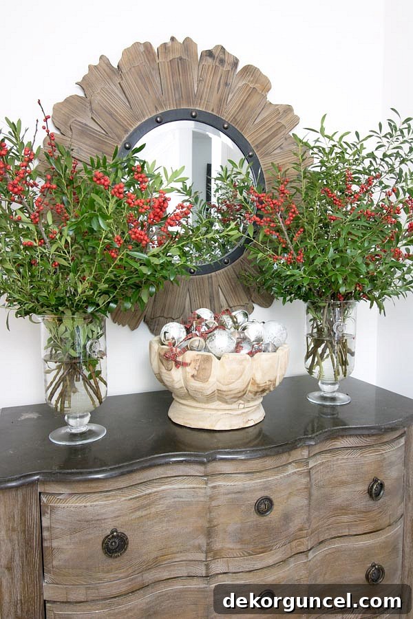 Christmas home tour - a bowl full of ornaments flanked by vases of boxwood branches and berries for entryway Christmas decor