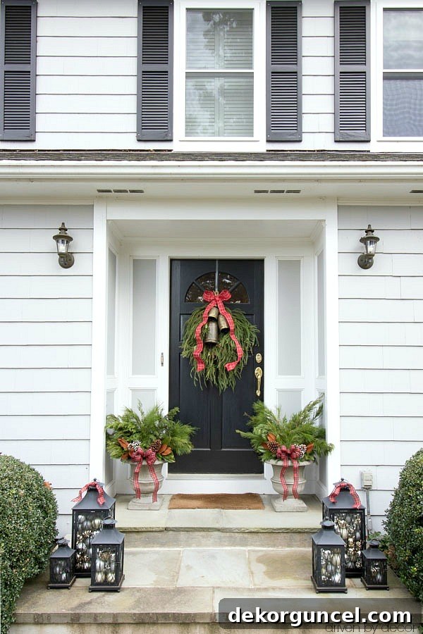 Christmas house tour - a trio of lanterns filled with ornaments, planters filled with greenery, and a greenery swag on the front door are simple porch decorations for Christmas