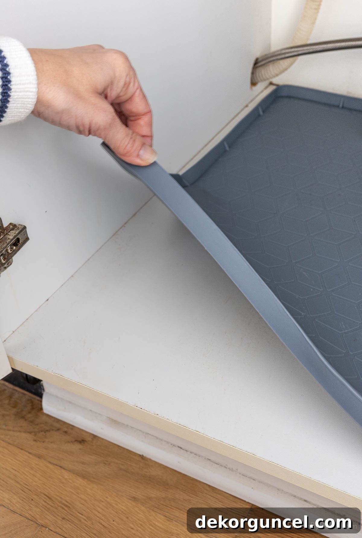Organizing Under the Kitchen Sink: A Guide to a Tidy Space 3 A gray silicone liner with a lip installed in an under-sink cabinet.